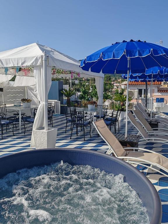 a hot tub on a patio with chairs and umbrellas at Blu D Alia Exclusive Rooms in Ischia Town