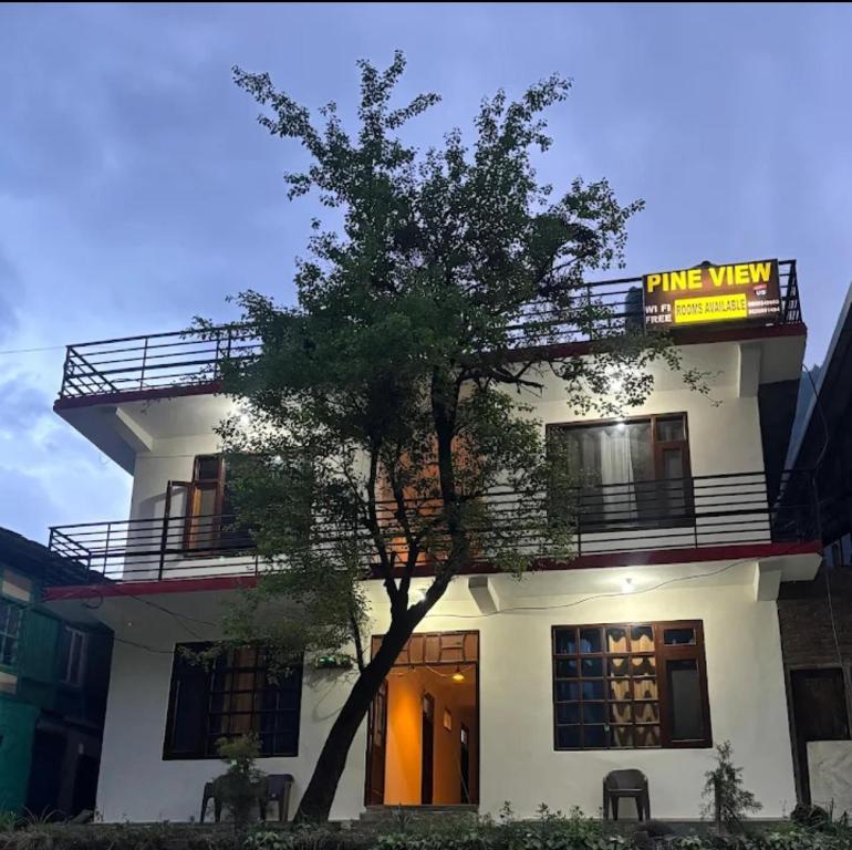 a white building with a tree in front of it at The Pine View in Kasol