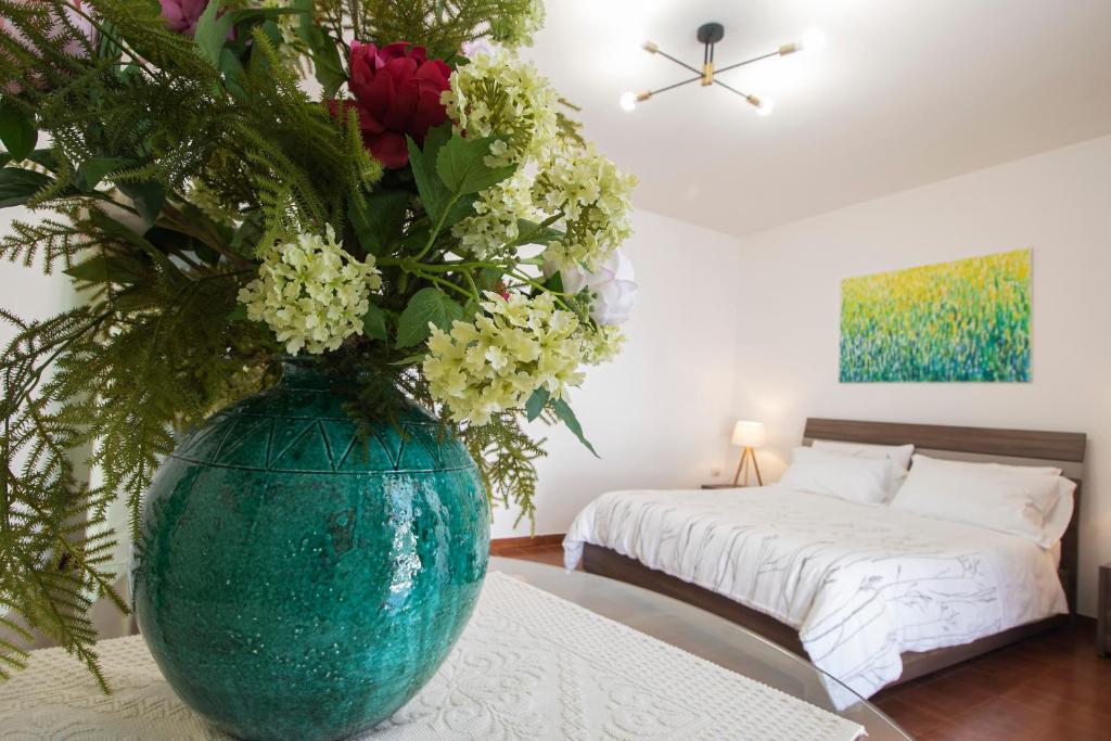 a blue vase with flowers on a table in a bedroom at Anthyllis Apartment in Alghero