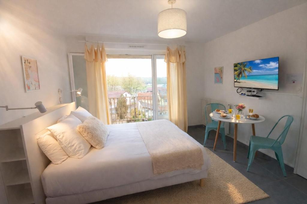 a bedroom with a bed and a table and a window at Le Candy- Appartement de charme à Digoin in Digoin