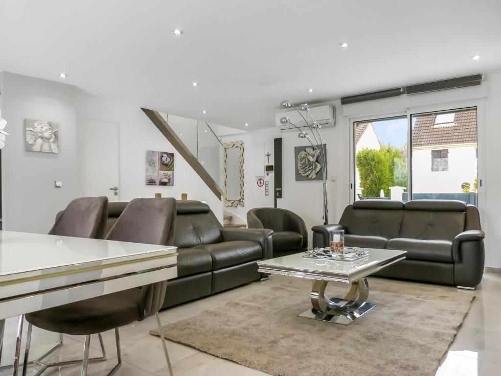 a living room with leather furniture and a table at Grande villa T6 avec piscine à 30 min de Disneyland Paris in Coulommiers