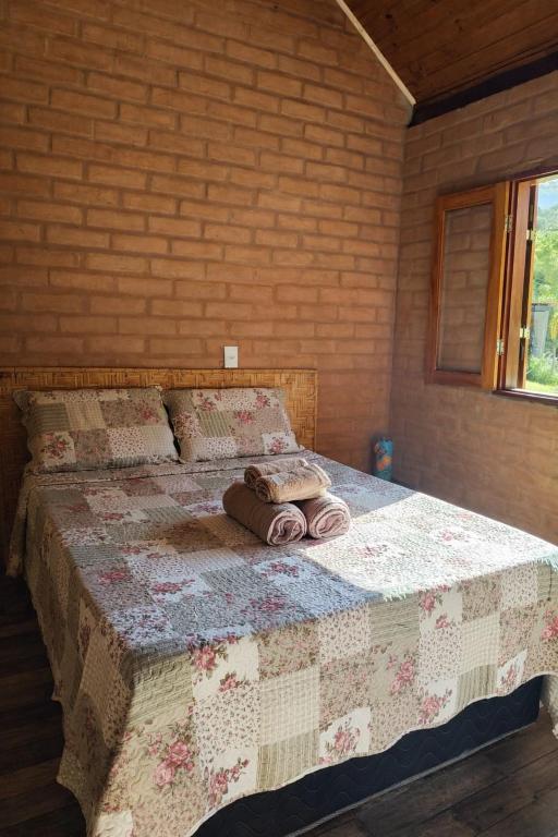 a bedroom with a bed with towels on it at Chalés Beira Rio in Santo Antônio do Pinhal