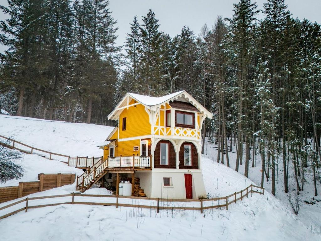 a yellow house in the snow with trees at Edelweiss Village & Resort – Chalet Heimann in Golden