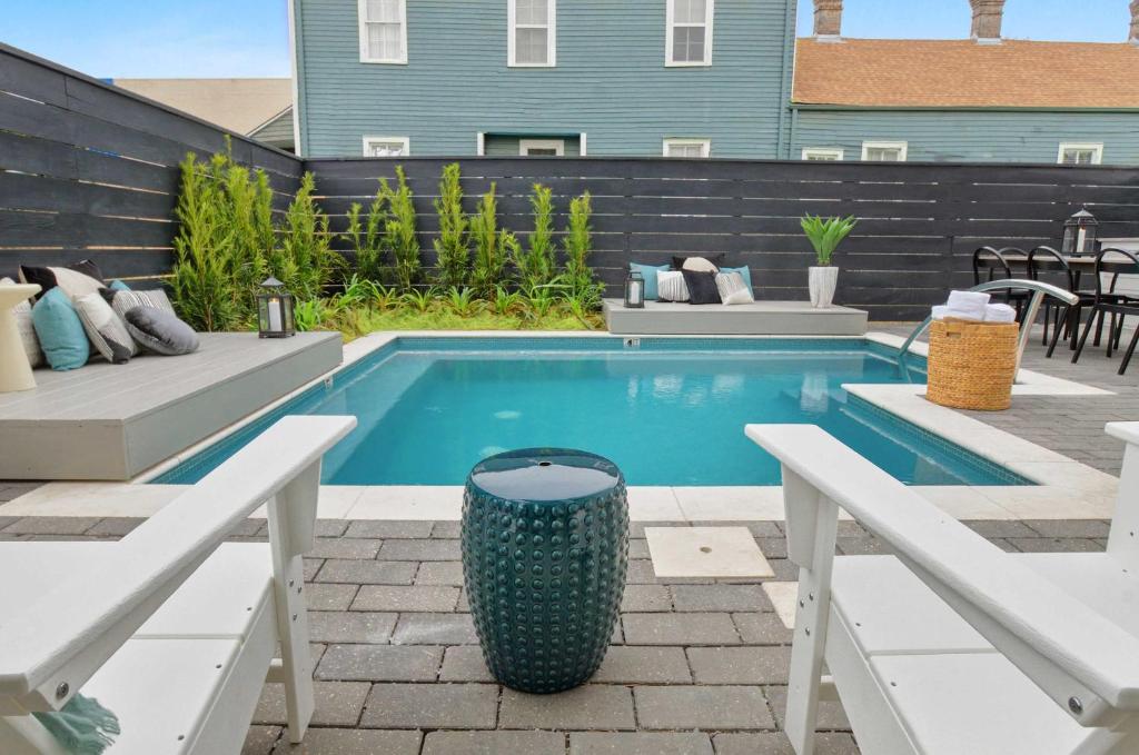 a swimming pool in a backyard with two benches at 14BR Downtown Combo & Shared Seasonal Pool in New Orleans
