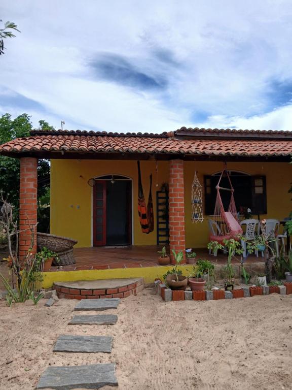 a yellow house with a porch and a patio at Quarto Privativo e Camping em Canoa Quebrada in Canoa Quebrada