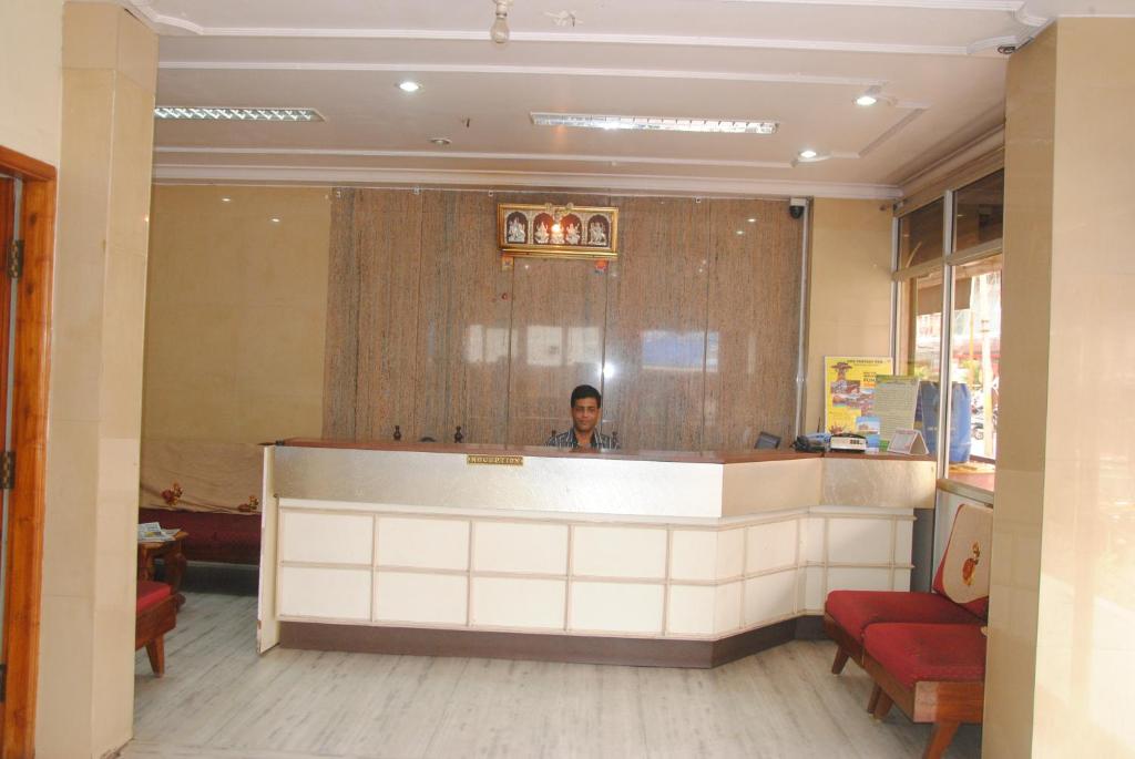 a man standing behind a counter in a restaurant at hotel sangeeth lodging in Mysore