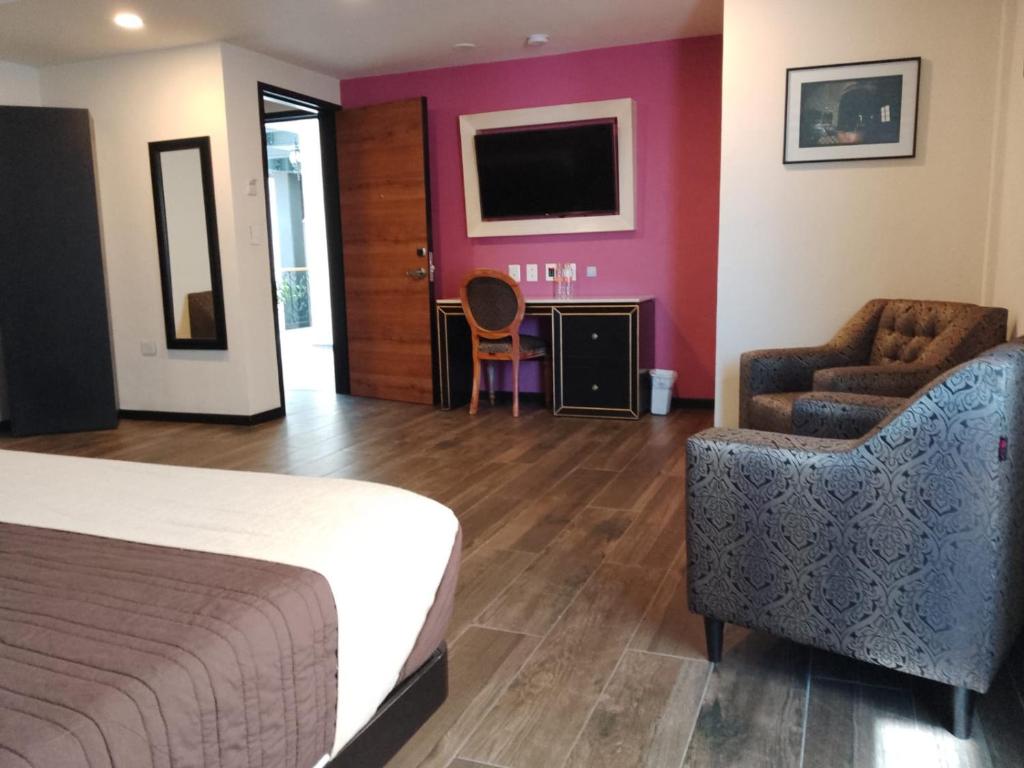 a hotel room with a bed and a chair and a television at Mansion Azul Cholula in Cholula