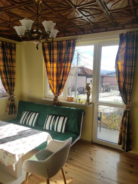 a living room with a green couch and a window at Апартамент за гости Вамсон in Velingrad