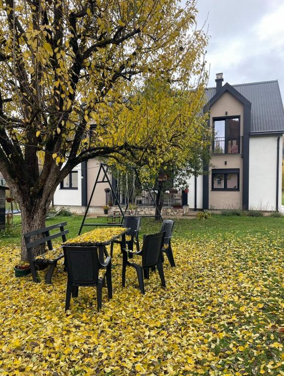 a table and chairs in a yard with leaves on the grass at Villa Villekulla in Kolašin