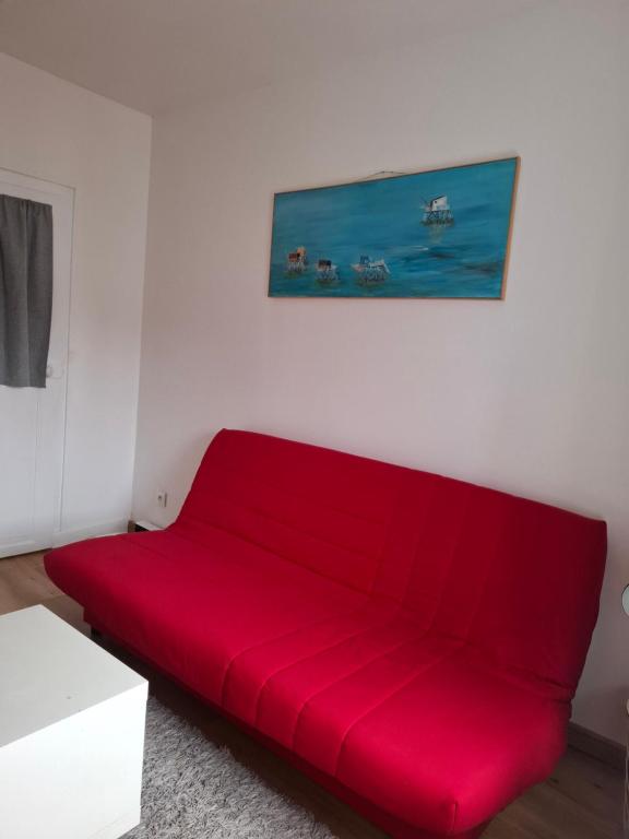 a red couch in a room with a painting on the wall at Escale cosy à Blois in Blois