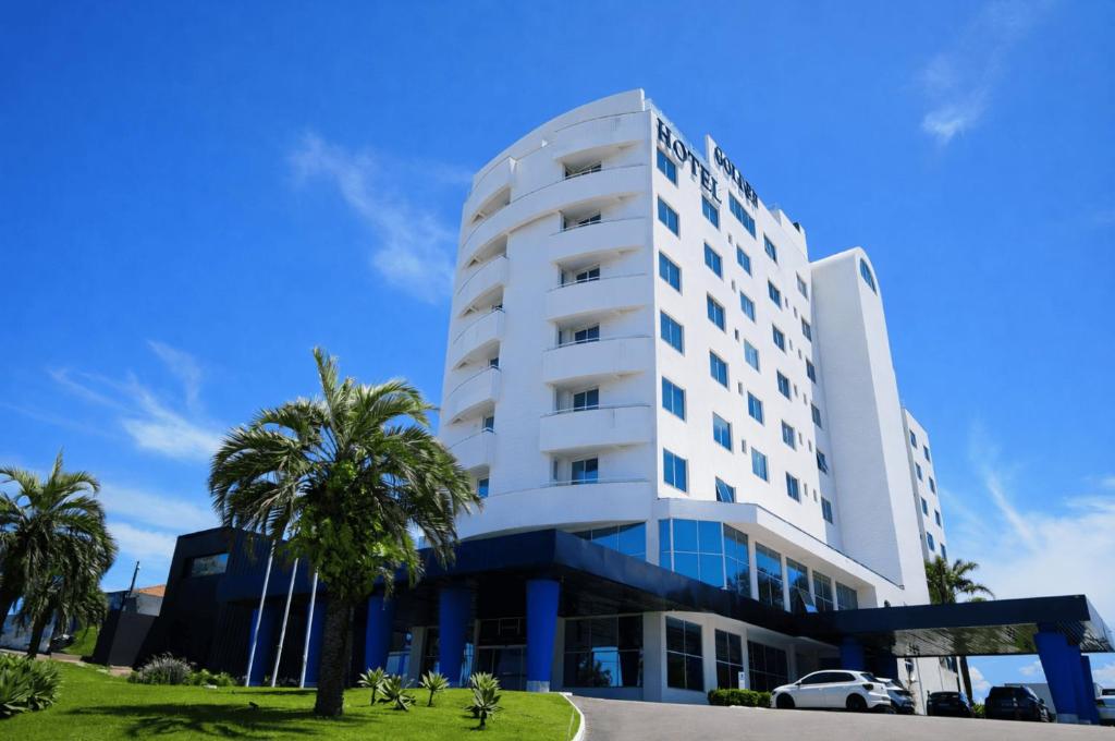 a white building with palm trees in front of it at Favorita Golden Hotel e Eventos in São José