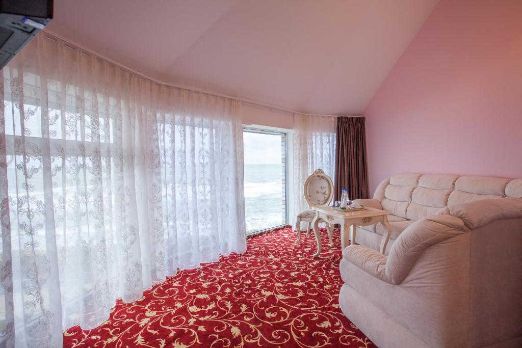 a living room with a couch and a large window at Hotel Zolotaya Milya in Zelenogradsk