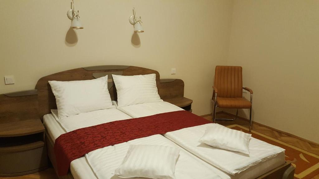 ein Schlafzimmer mit einem Bett mit weißer Bettwäsche und einem Stuhl in der Unterkunft Satu Mare Apartments in Satu Mare