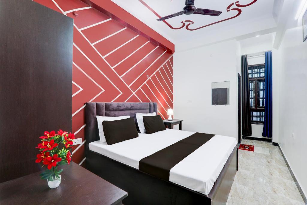 a bedroom with a bed and a red wall at Hotel O Kp Guest House in Bāra Banki