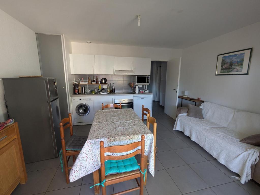 a kitchen and living room with a table and a couch at T2 Château vert in Le Grau-dʼAgde