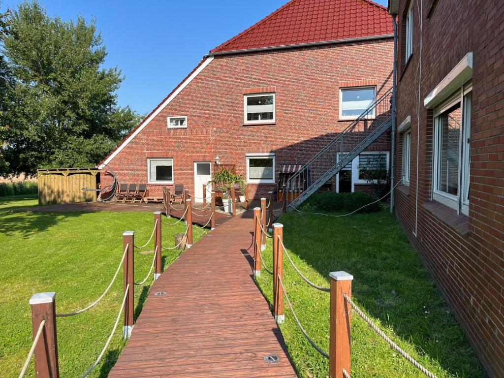 a wooden walkway in front of a brick building at Ferienhof Harlenest in Wittmund