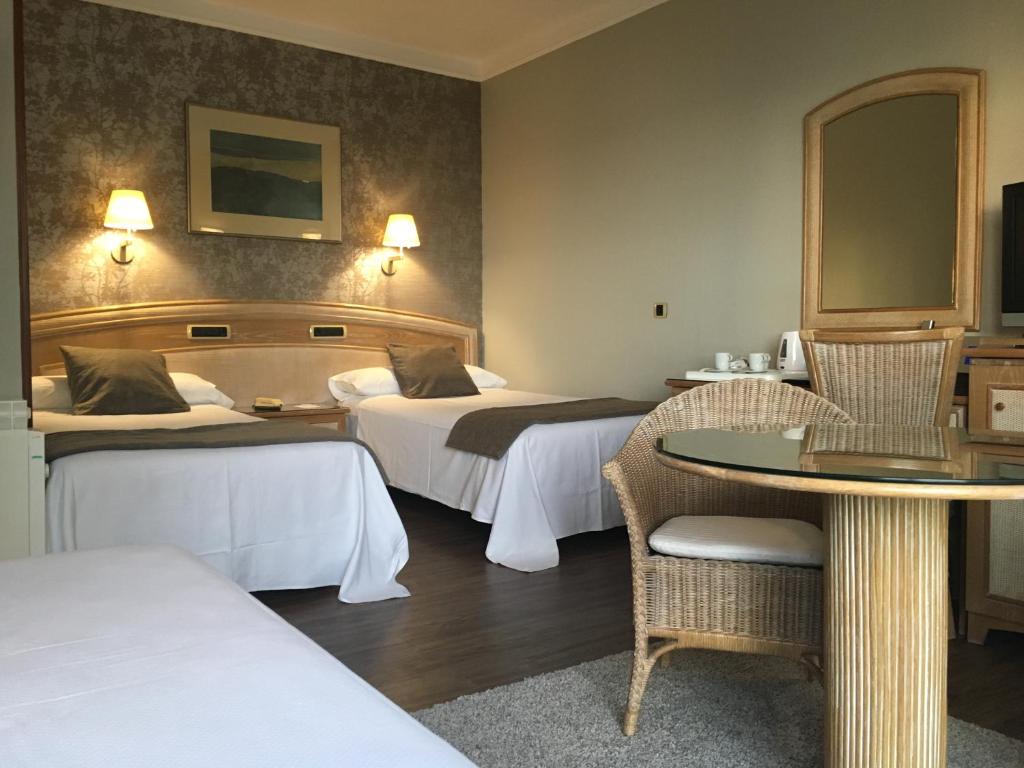 una habitación de hotel con dos camas y una mesa en Las Rocas Playa Hotel, en Castro Urdiales