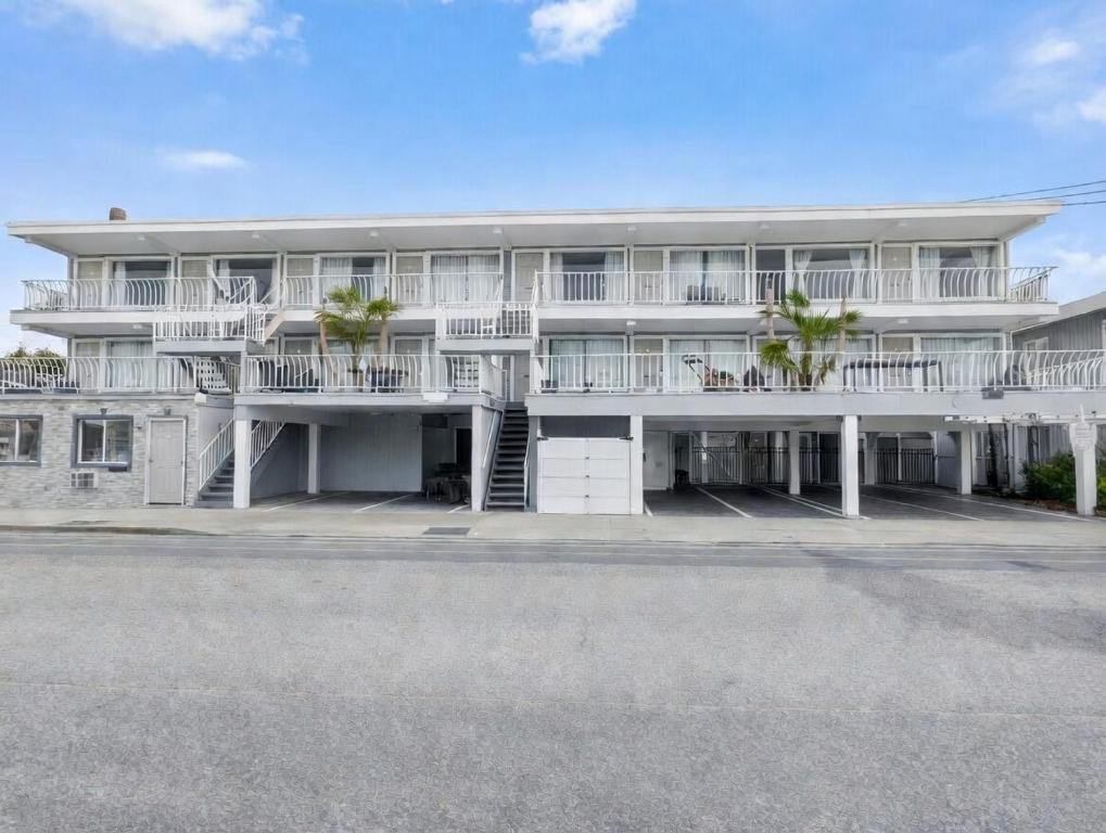 a large white building with balconies and a street at Sunset Beach Hotel in Wildwood