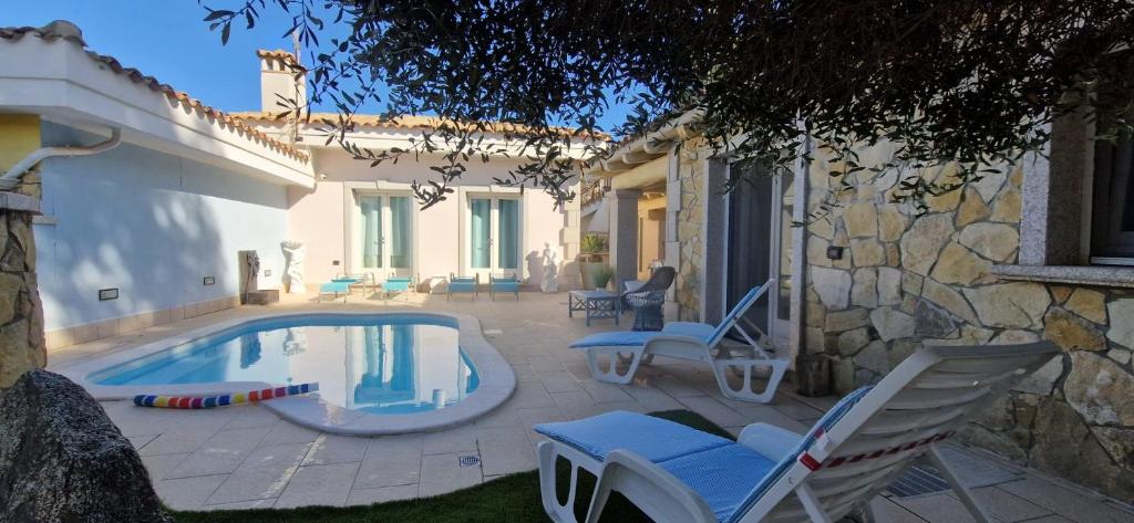a swimming pool with chairs and a house at Casa Sinzias con piscina 9 posti letto in Castiadas