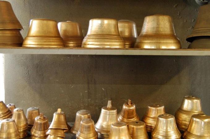 a bunch of gold bells sitting on shelves at Les Clarines in Mouthe