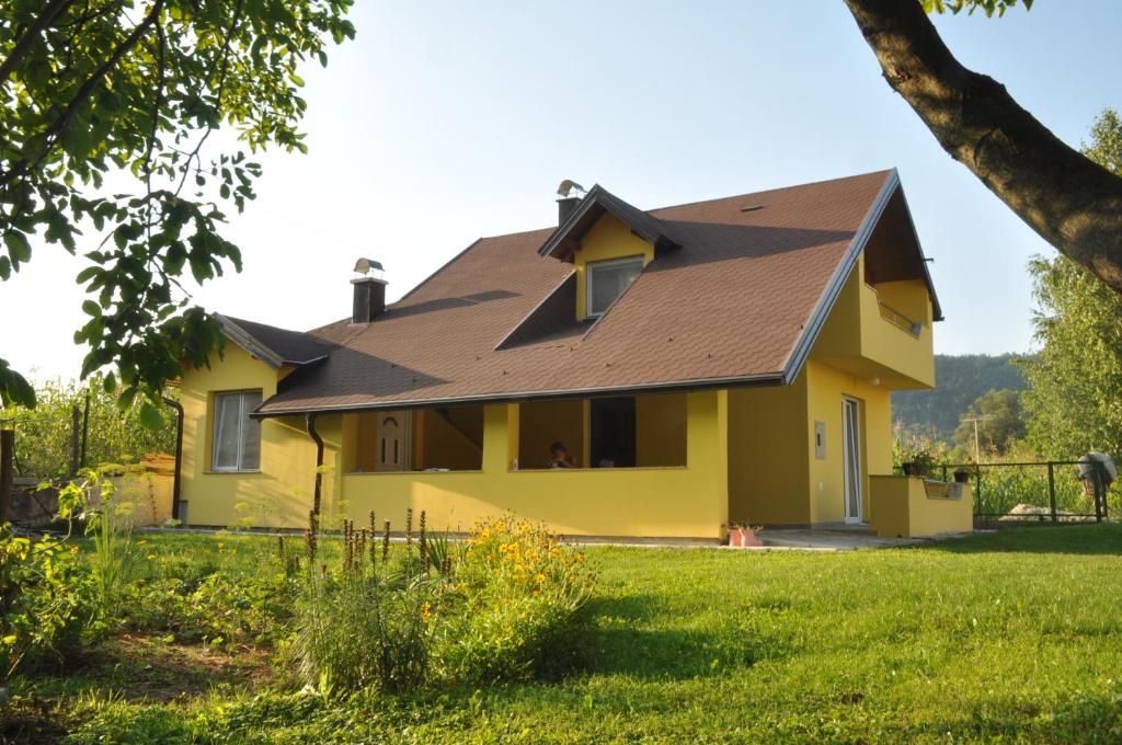a yellow house with a brown roof at Kuća za odmor Komić in Smrdan