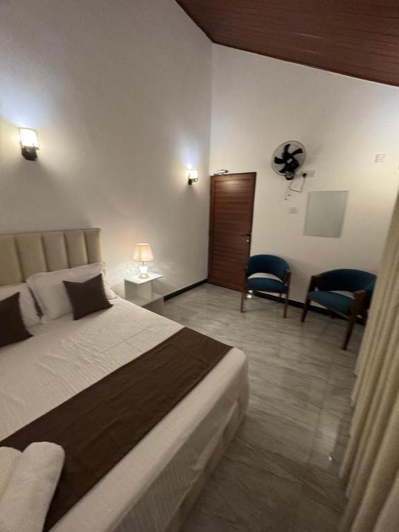 a bedroom with a bed and two chairs in a room at Blue Rock Retreat in Belihuloya