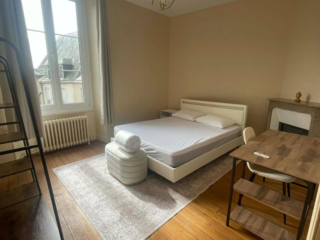 a small bedroom with a bed and a table at Le Louis d'Or in Beaumont-sur-Sarthe
