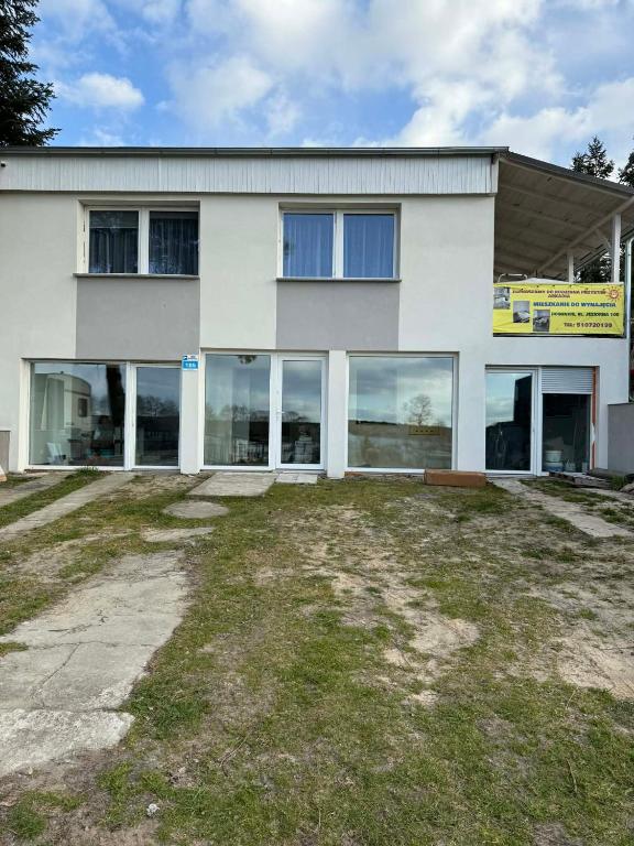 a white building with large windows and a yard at Rodzinna Przystań Arkadia in Dominice
