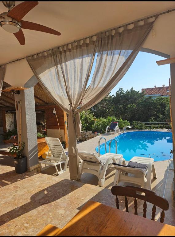 a patio with a pool and chairs and a umbrella at Apartmani Kasteljan 12, Stara Novalja in Stara Novalja