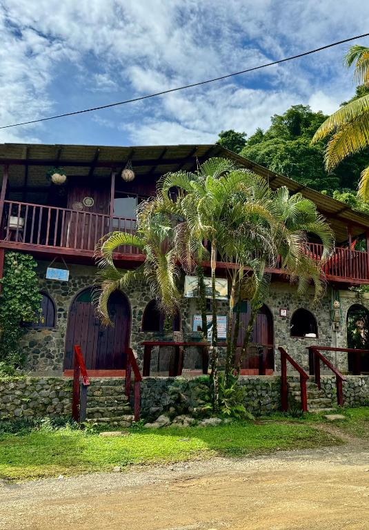 a house with palm trees in front of it at Posada Turística Rocas De Cabo Marzo in Bahía Solano