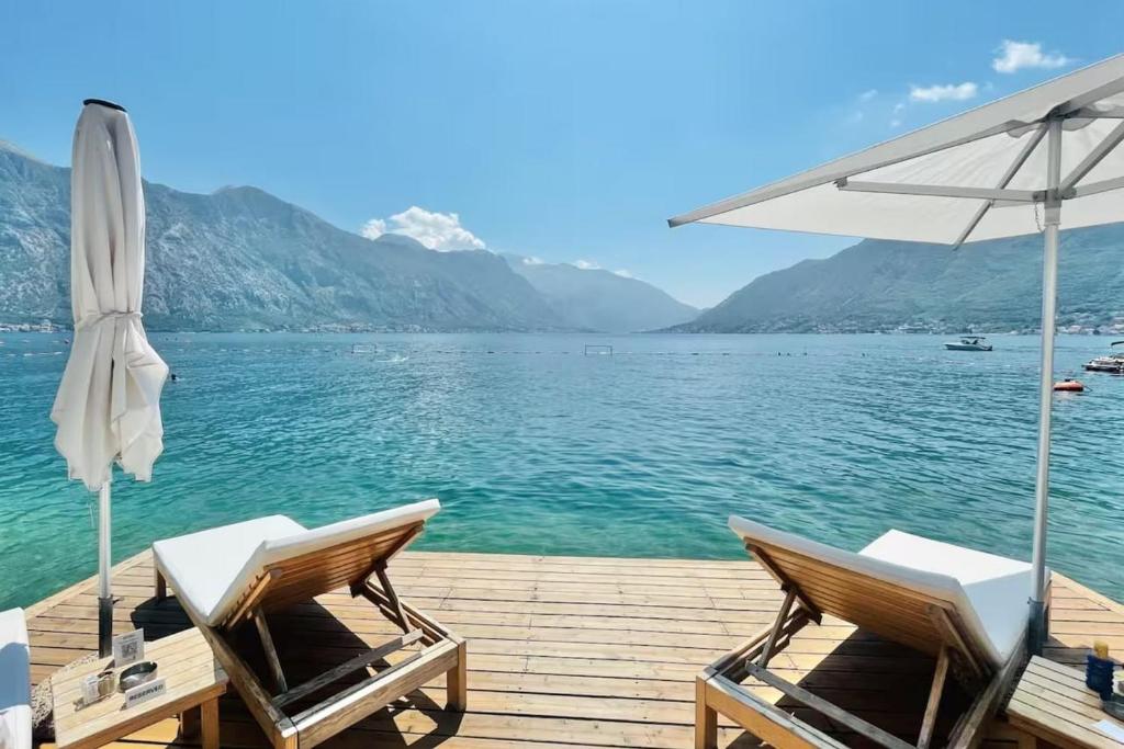 a pair of chairs and an umbrella on a dock at Private Terrace Living - Blue Flag Beach & Family Retreat near Kotor in Gornji Orahovac
