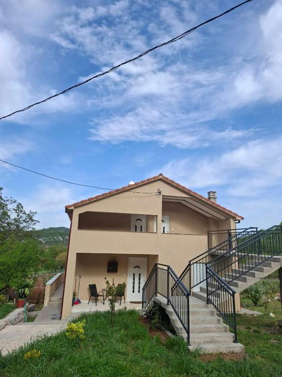 a house with a staircase in front of it at Apartmani Suvodoli in Rvaši