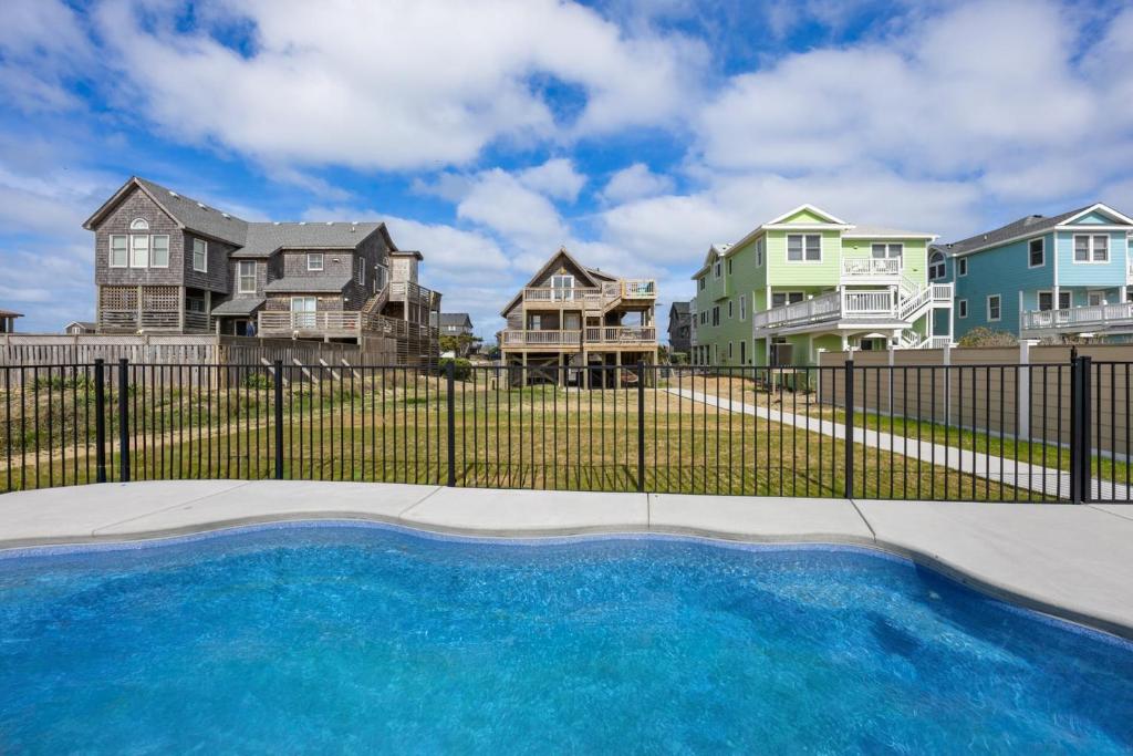 a pool in front of a fence with houses at 6129 - Lady Jane in Nags Head