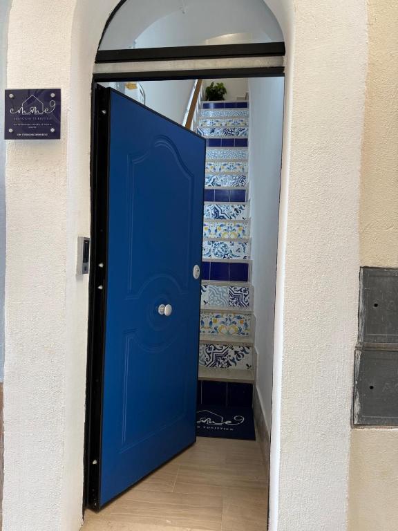 a blue door leading to a staircase with blue and white dishes at Emme9 in Gaeta