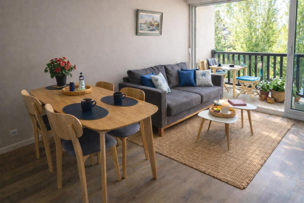 a living room with a table and chairs and a couch at Le refuge Marin - Mer, Piscine, tennis & Loisirs à 2 pas in Cabourg