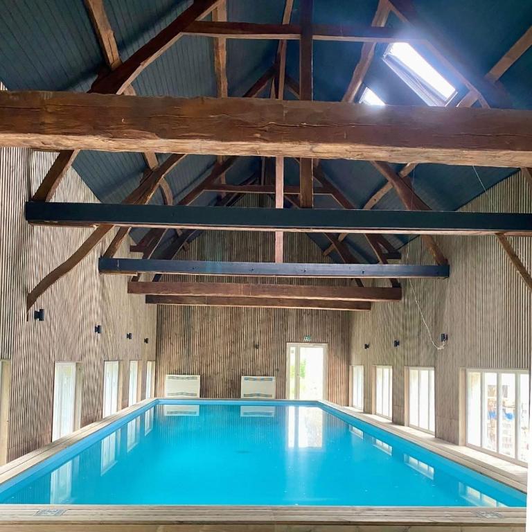 an indoor swimming pool with blue water in a building at Logis cosy avec piscine in Saint-Josse