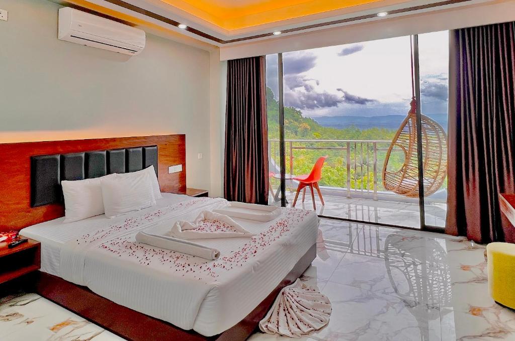a bedroom with a bed and a balcony with a view at Cloudy Inn Resort in Bāndarban