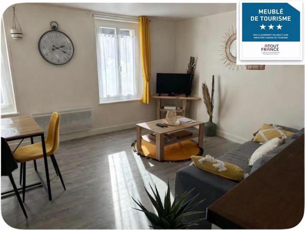a living room with a couch and a clock on the wall at Gîte des hallettes in Fécamp