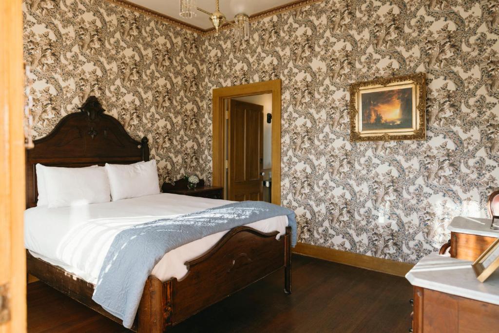 a bedroom with a bed and a wall covered in wallpaper at Cosmopolitan Hotel in San Diego