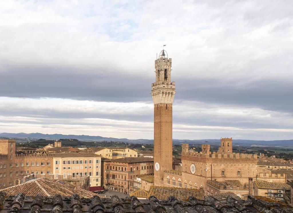 a tall clock tower in the middle of a city at Il NIDO-Attico Siena Centro con vista Duomo e Torre Del Mangia in Siena