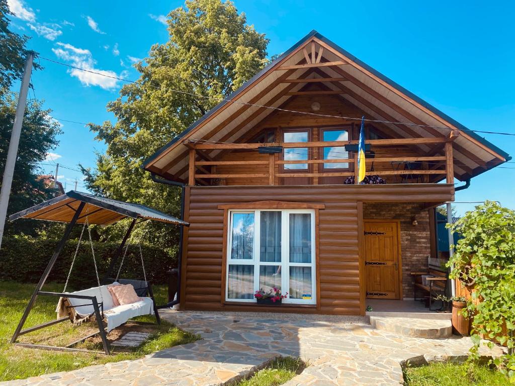 a log cabin with a porch and a swing at Карпатська Тиша in Utoropy
