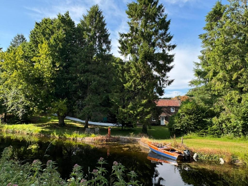 a boat on a river with trees and a house at Idyllic Waterside Cottage in Mid Devon in Tiverton