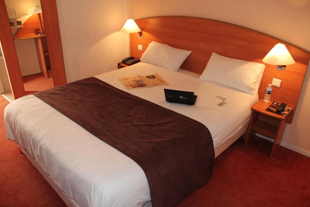 a hotel room with a large bed with a book on it at Central Hotel in Créteil