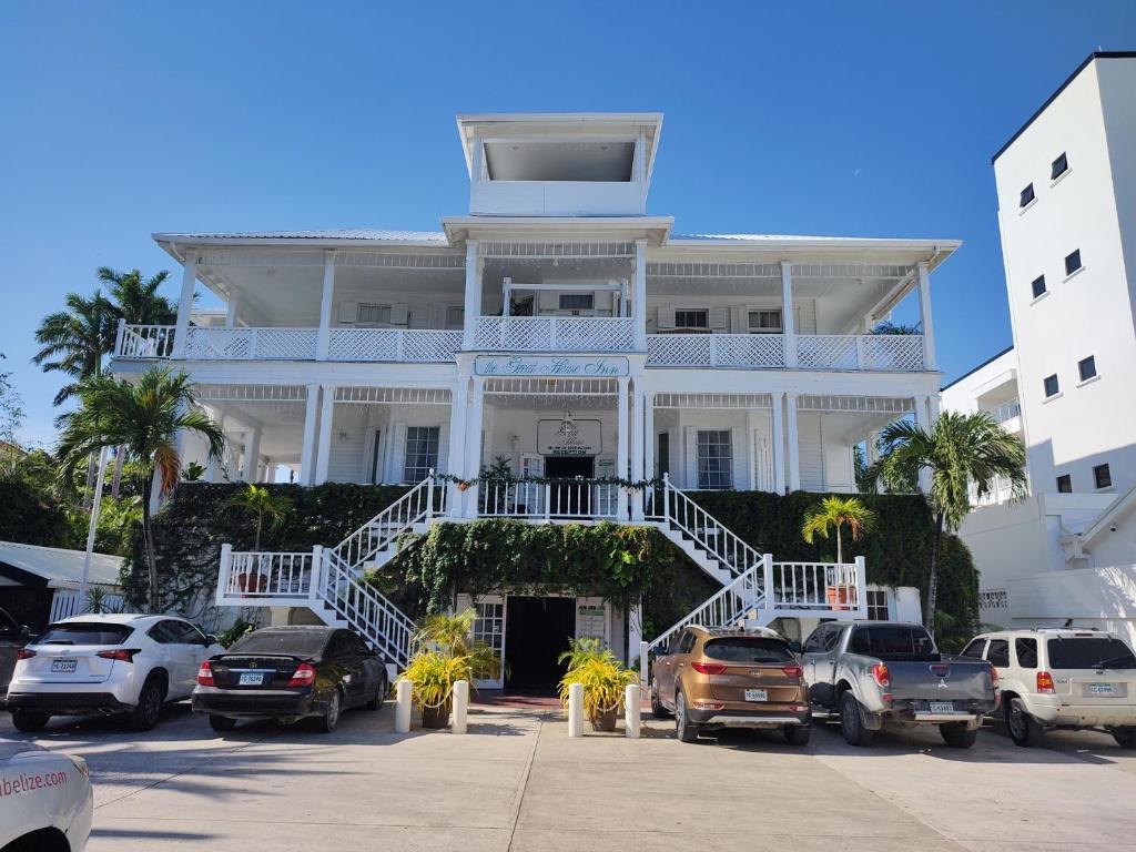 a large white building with cars parked in a parking lot at The Great House Inn in Belize City
