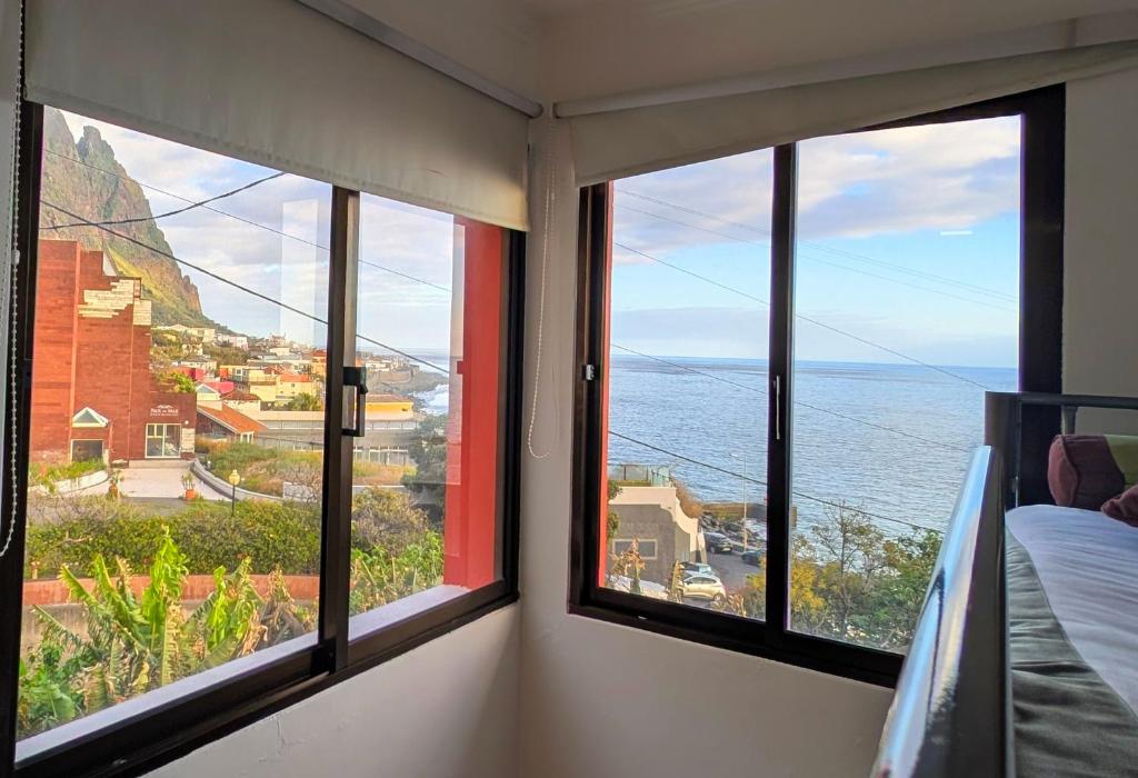 a room with three windows with a view of the ocean at Paul do Mar view in Paul do Mar