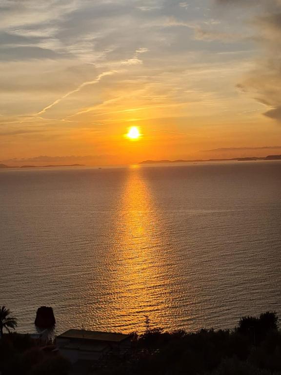 a sunset over the ocean with the sun setting at RAMA APARTAMENT in Vico Equense