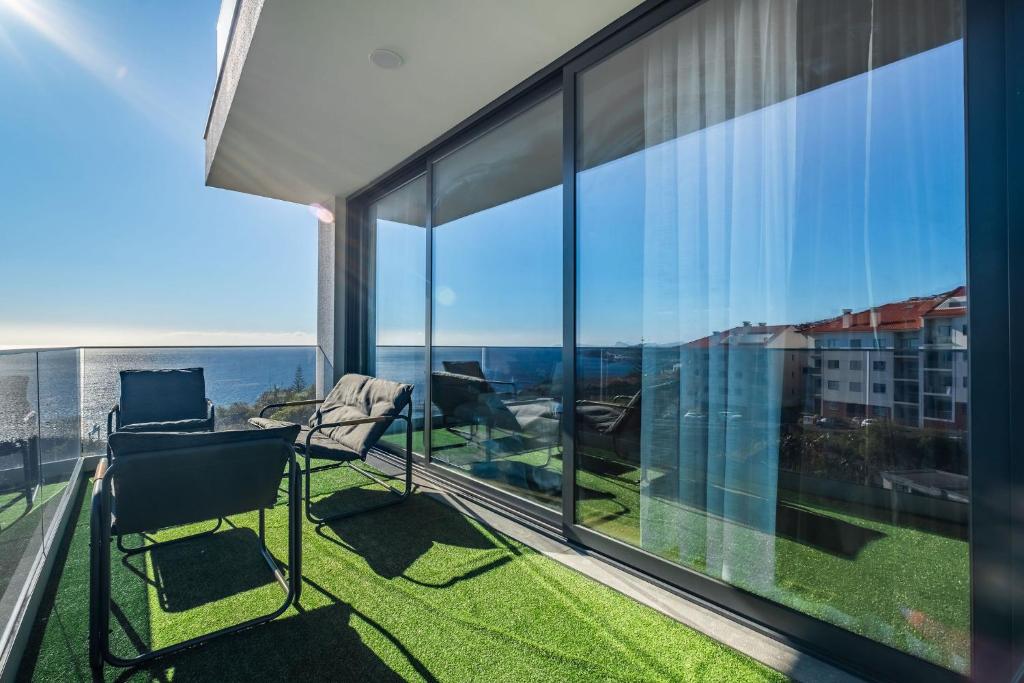 a balcony with a chair and a view of the city at Endless Horizon BY YOUR KEY MADEIRA in Santa Cruz