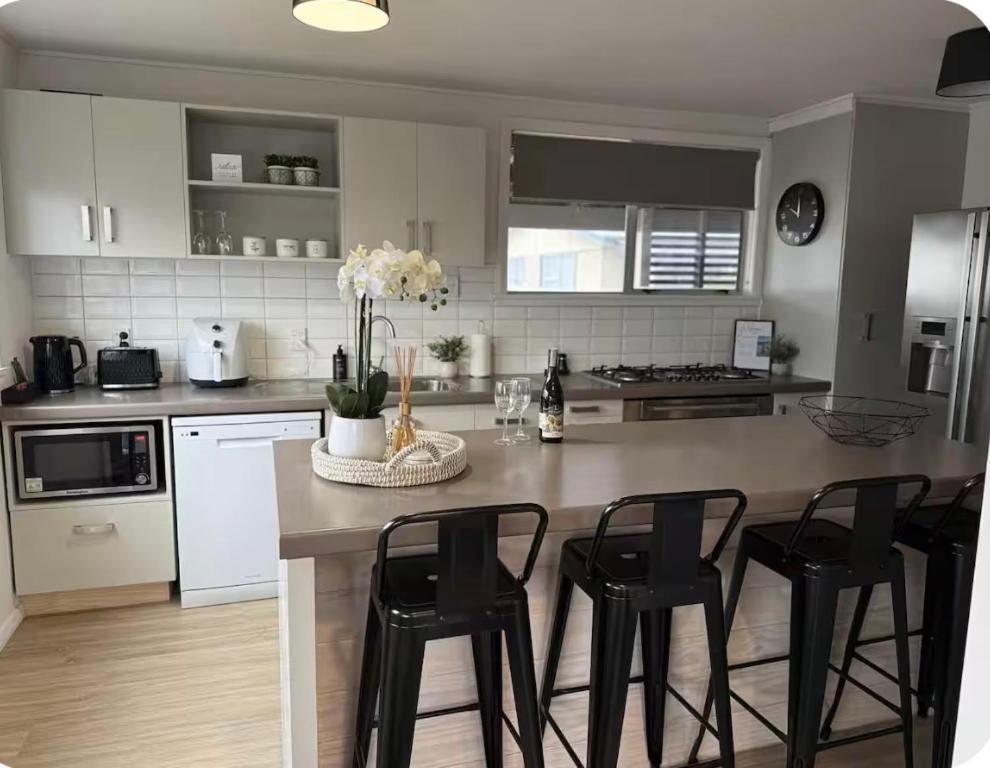 a kitchen with a island with black chairs in it at Relax at Jollie-Cozy 3-Bedroom Home, Central Twizel in Twizel