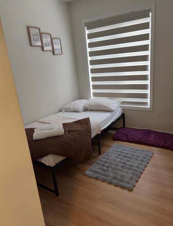 a bed in a room with a window and a rug at Sandell Place in Oshawa