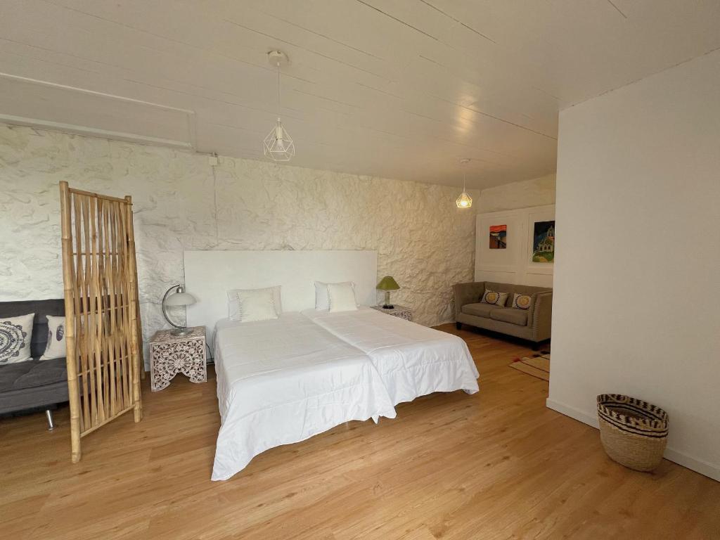 a bedroom with a white bed and a couch at Casa do Cacto - Studio Flat in Madalena